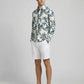 Side view of a man modeling the botanical print textured long sleeve shirt with white shorts.