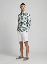 Side view of a man modeling the botanical print textured long sleeve shirt with white shorts.