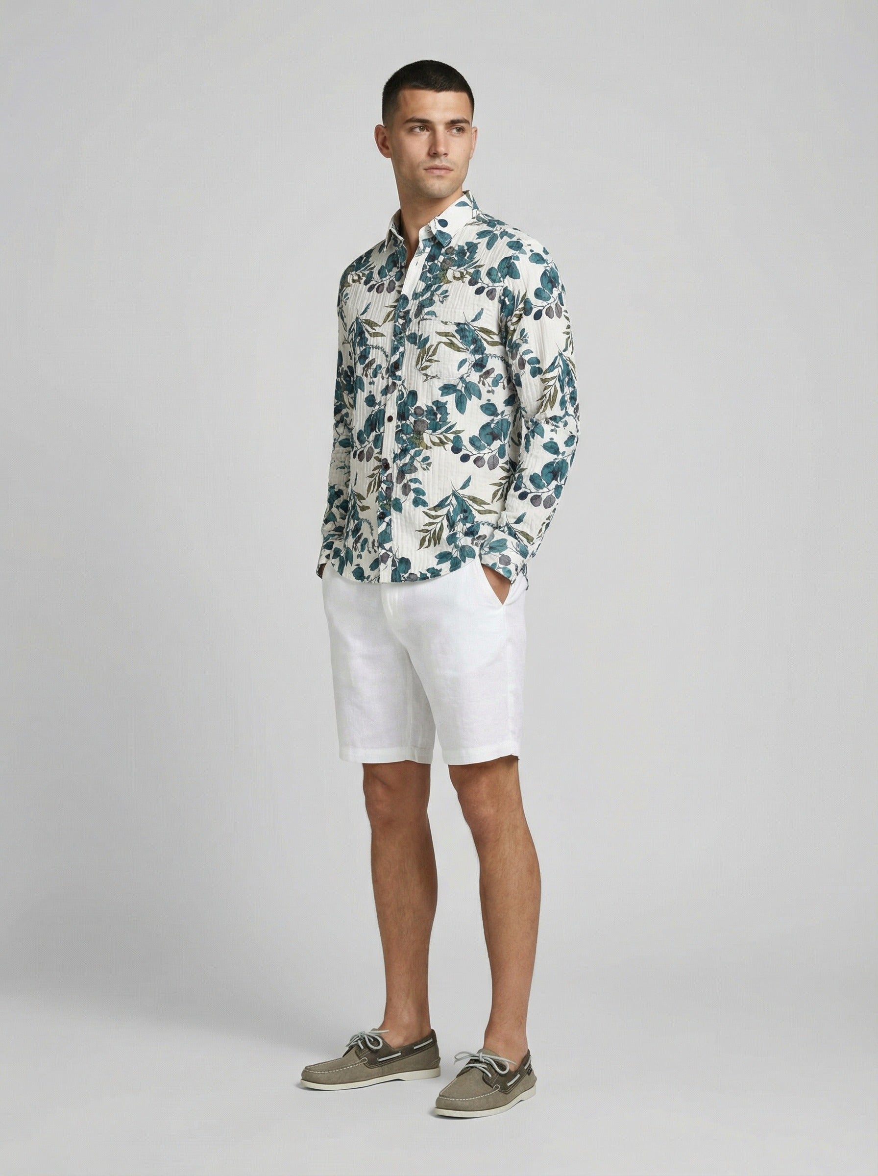 Side view of a man modeling the botanical print textured long sleeve shirt with white shorts.