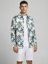 Man wearing the botanical print shirt layered open over a plain white t-shirt and white shorts.